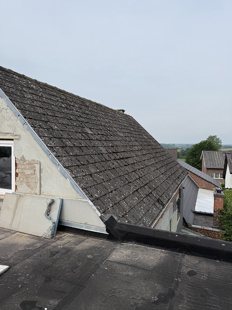 Voor de dakrenovatie in Dendermonde, zichtbaar met verweerde en mosbegroeide dakpannen.